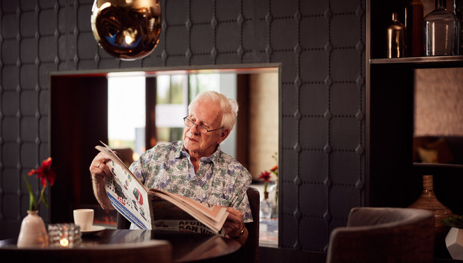 Mann liest Zeitung in der Brasserie